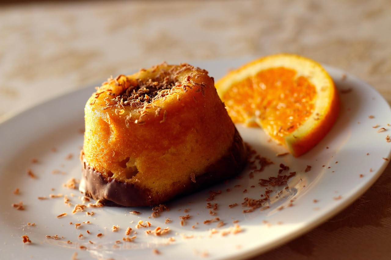 Babà salato a forma di ciambella su piatto bianco, farcito di ricotta e salumi, con ragù di verdure, decorato con prezzemolo fresco