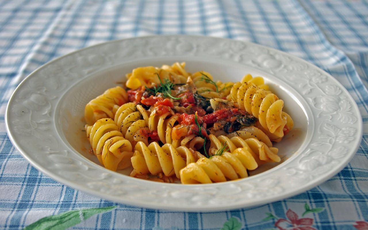 Battuto di alici cremoso color grigio-bianco in ciotola bianca, preparato con alici fresche, sale e posate da cucina vintage su tavolo di legno scuro