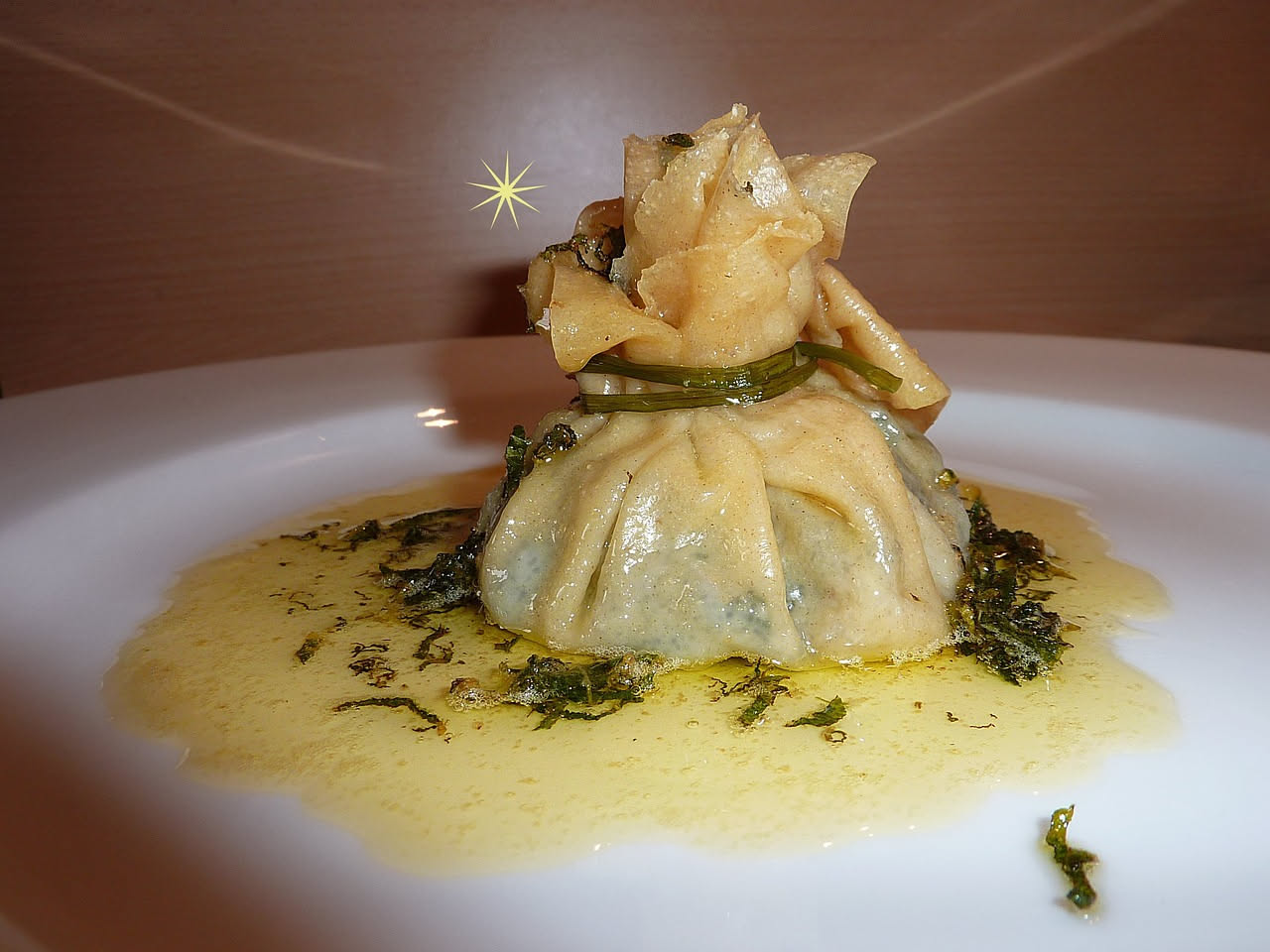 Borragine fresca cucinata in padella, foglie verdi scure raccolte insieme, olio lucido e spicchi d'aglio dorato