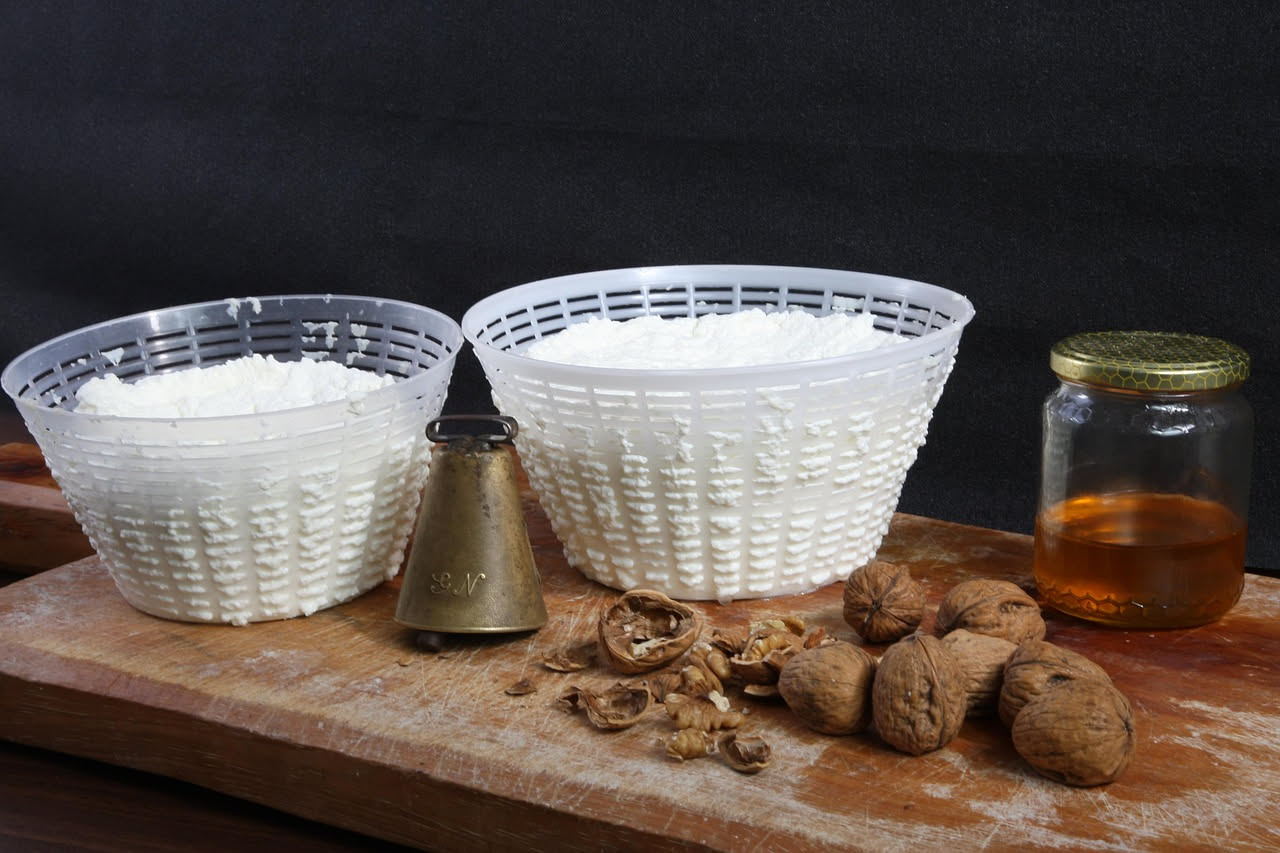 Cacioricotta bianca e cremosa in una ciotola di ceramica con accanto una tazza di latte e un termometro da cucina