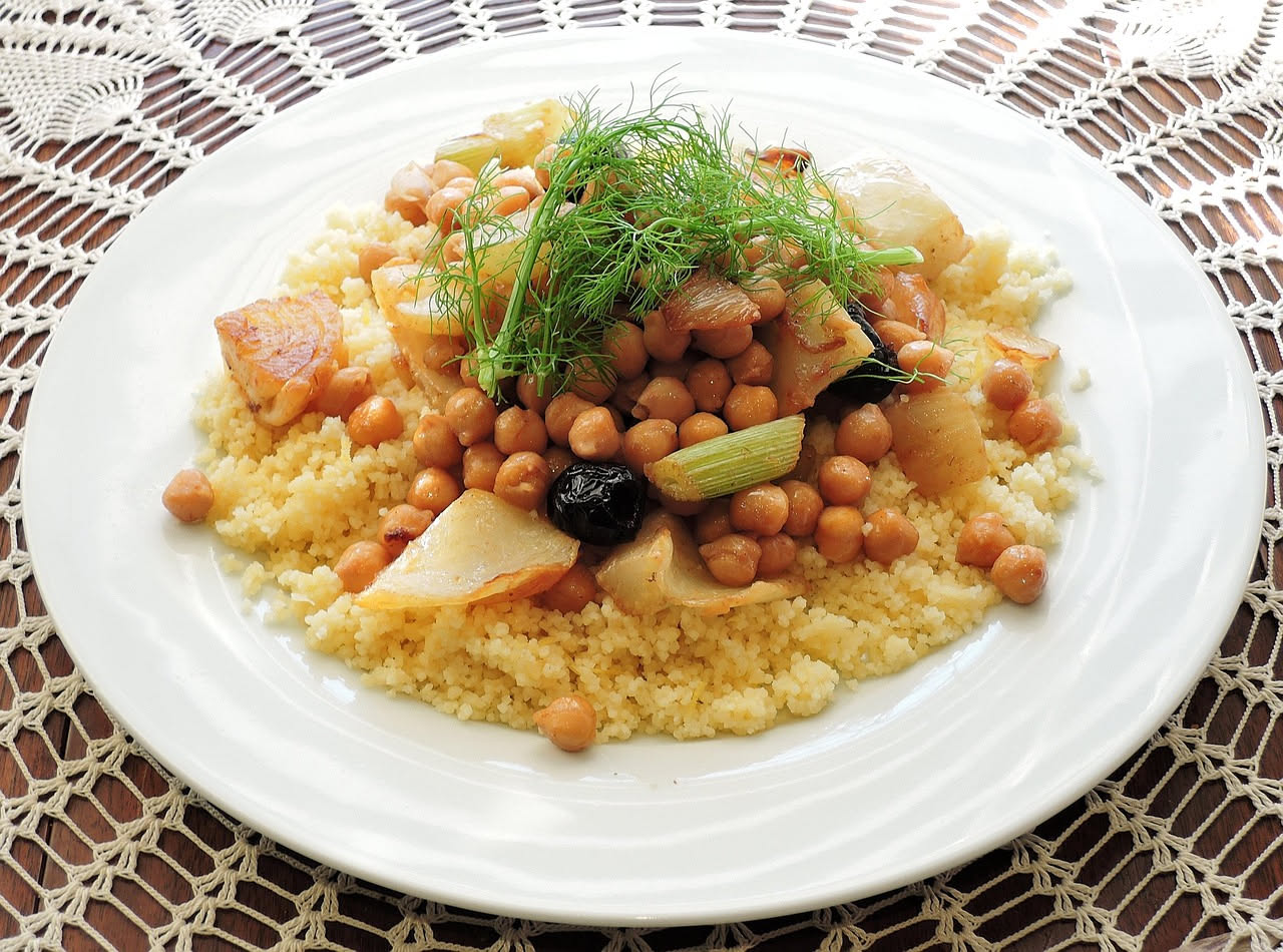 Ceci beige in salsa densa con cipolle morbide e dorate, in una ciotola di ceramica bianca, un filo d'olio verde in superficie