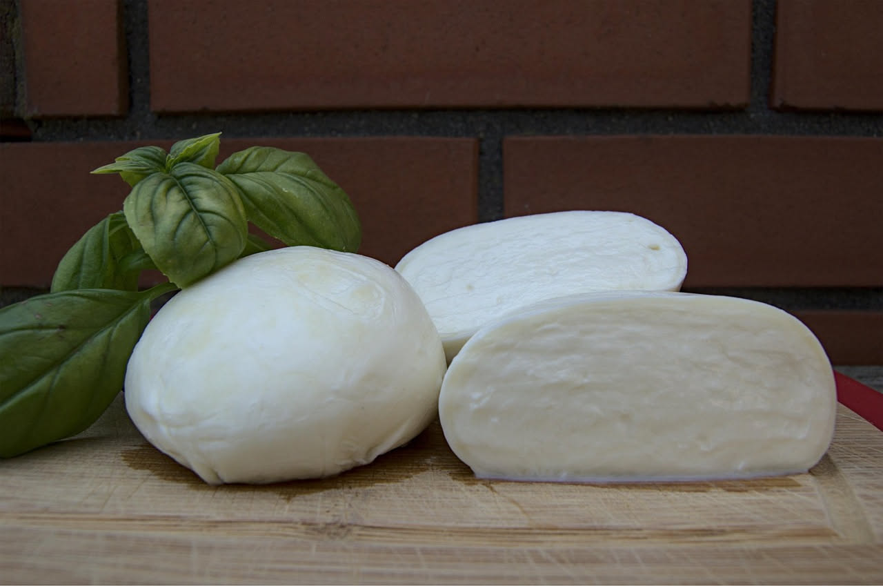 Fior di latte appena formato, bianco e lucido, ancora caldo, staccato con un cucchiaio da latte bollente. Accanto una ciotola con acqua salata gelida.