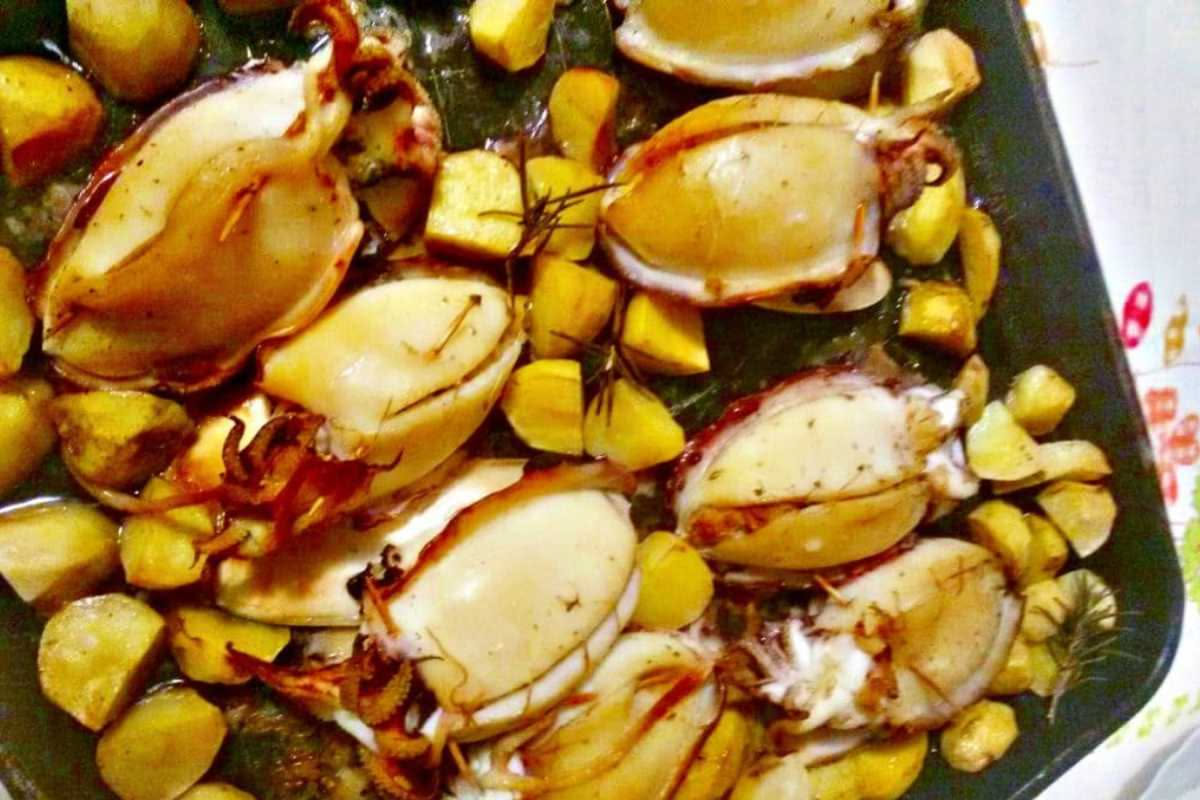 Quattro involtini di totano dorati in padella con olio, aglio e prezzemolo fresco, disposti su un piatto bianco con limone affettato