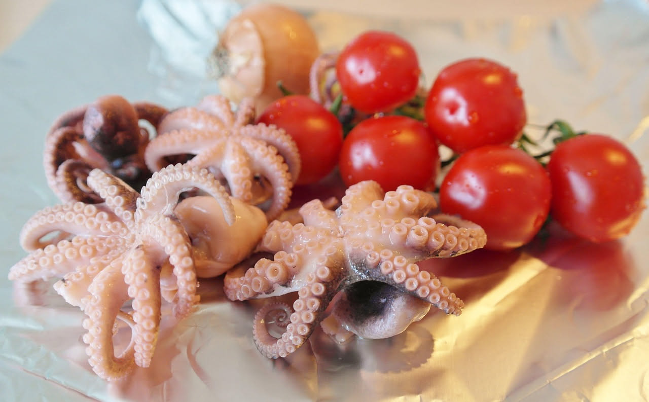 Polpo cotto tagliato a pezzi in una pentola con salsa di pomodoro, aglio e prezzemolo fresco