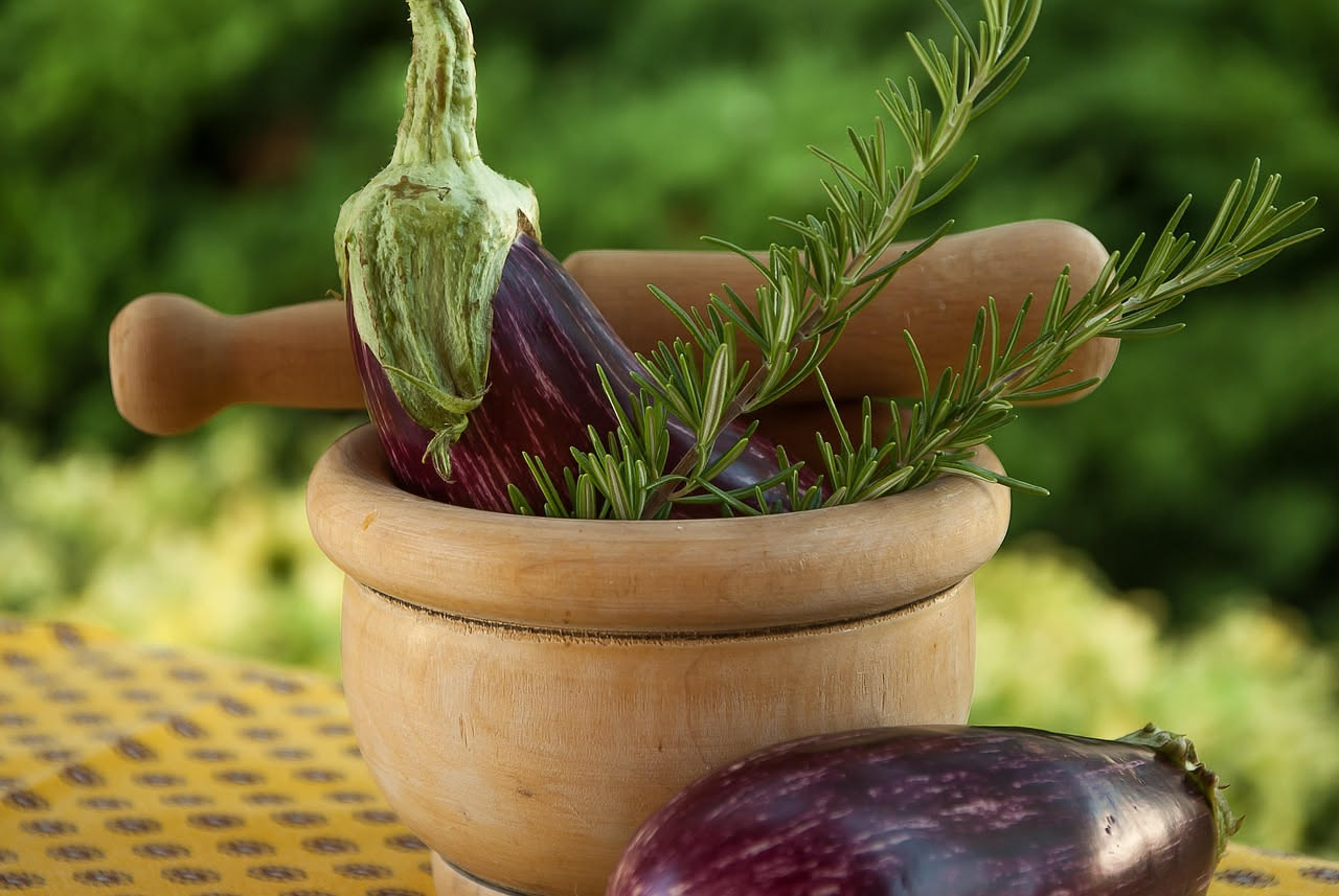 Ragù di melanzane denso e brunastro in una pentola di terracotta, con pezzi visibili di melanzana morbida, basilico fresco sopra, vapore leggero