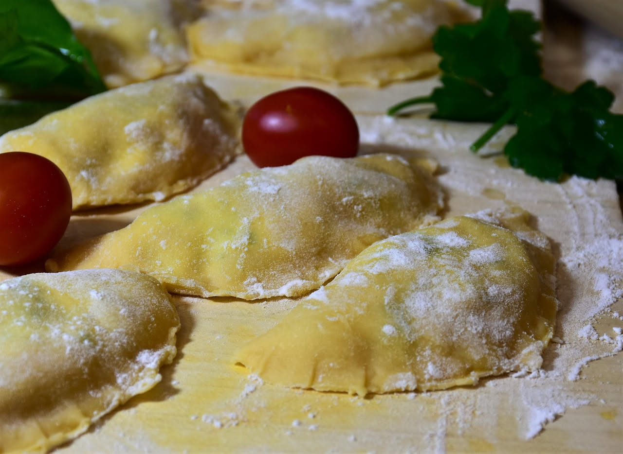 Piatto di urzi ca' pummaroru con pasta ripiena color tortora condita con sugo di pomodoro rosso, ricotta bianca visibile nel ripieno, cibo rustico su piatto di ceramica