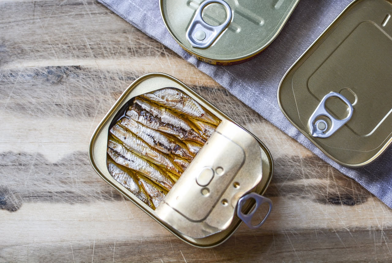 Acciughe marinate bianche e argentee in una ciotola di vetro con aceto, sale grosso e fette di limone fresco intorno