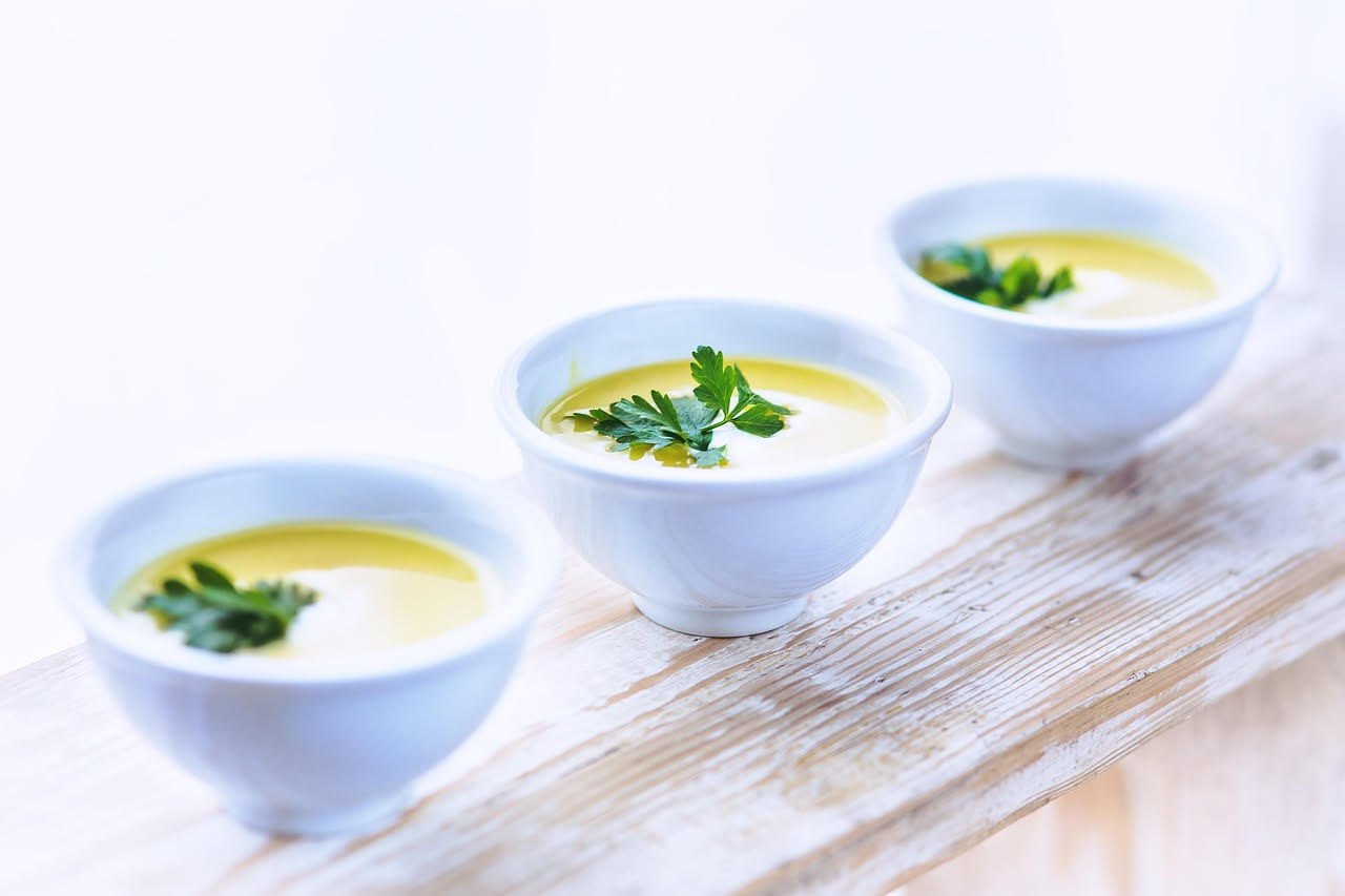 Bicchiere trasparente di acquasale con cristalli di sale marino visibili sul fondo, colore limpido e trasparente, accanto a insalata fresca di rucola e pomodori