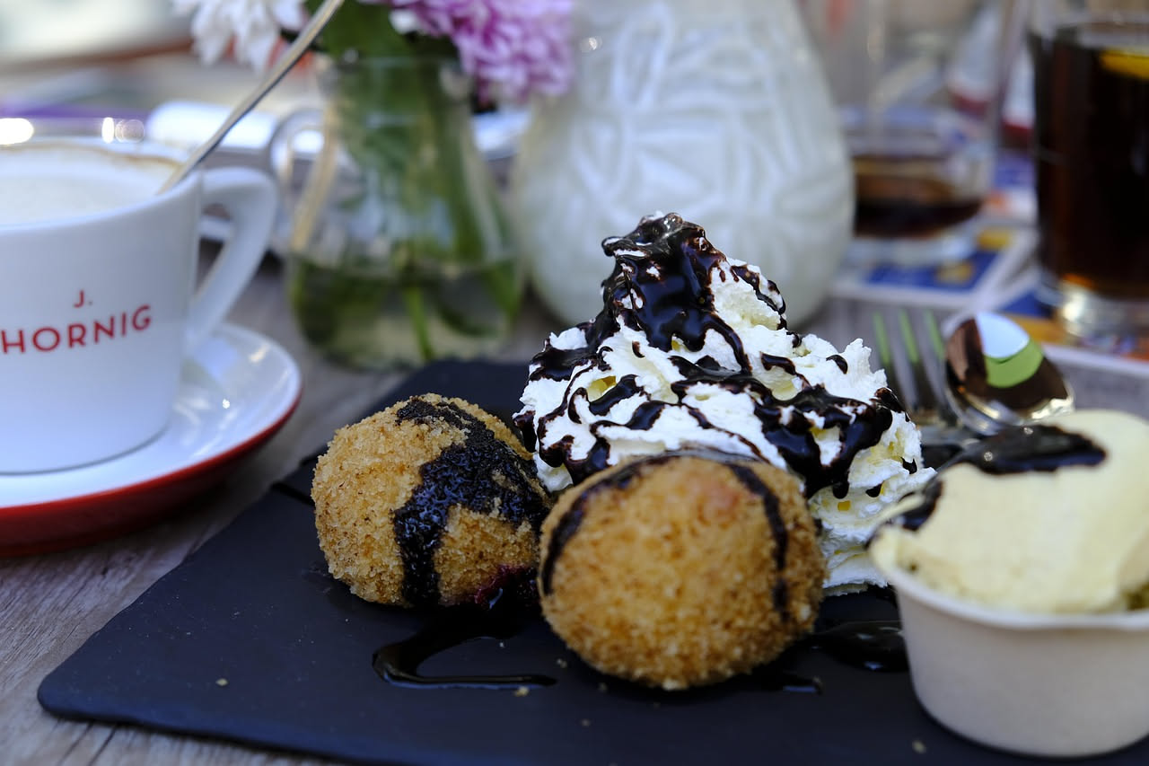 Quattro arancini dorati e croccanti disposti su un piatto bianco, tagliati a metà per mostrare il riso cremoso, il ragù e la mozzarella filante al centro