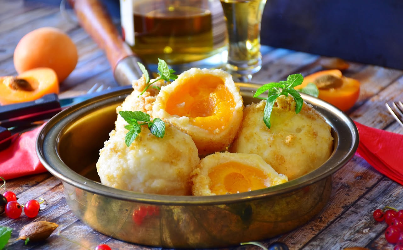 Ciotola con brodo caldo, tre arancini gialli morbidi galleggianti in superficie, spruzzati di prezzemolo fresco, con un piatto bianco e un cucchiaio accanto