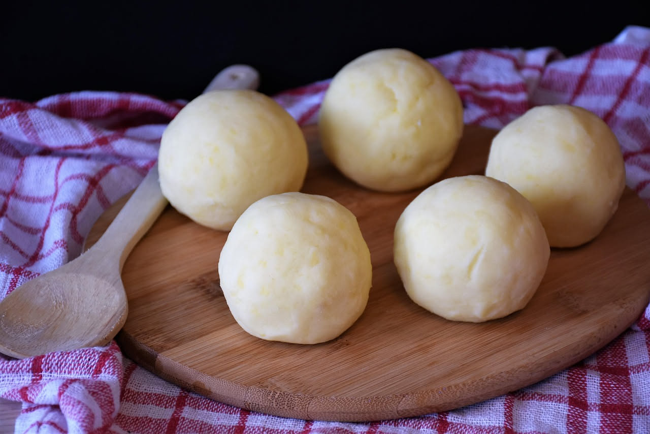 Tre arancini dorati e croccanti tagliati a metà su un piatto bianco, che mostra il ripieno interno di ragù marrone, riso cremoso e un pezzetto di burro giallo visibile.