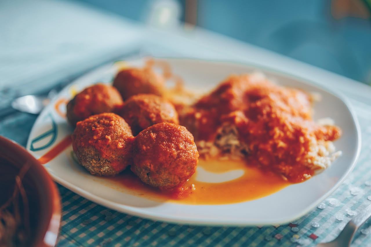 Tre arancini molisani dorati e croccanti disposti su un piatto bianco con contorno di ragù di carne, visibili le tracce della panatura croccante e il riso dorato all'interno