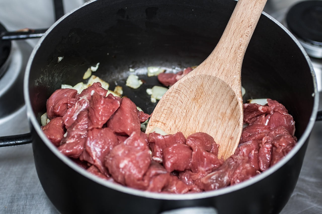Tranci di anguilla affumicata grigliati disposti su un piatto bianco, con segni di cottura scuri sulla pelle, contorno di limone fresco tagliato a spicchi e prezzemolo verde