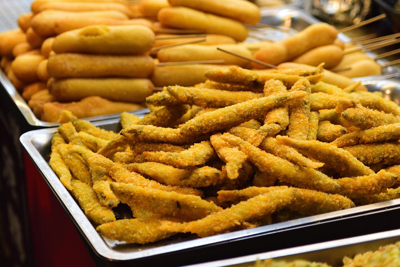 Fiori e foglie di borragine fritti, dorati e croccanti, su carta assorbente bianca con grani di sale marino grosso sparsi intorno