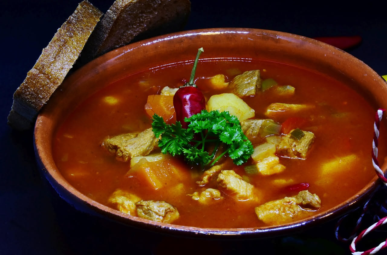 Brodetto savonese in ciotola bianca profonda con pezzi di calamari e seppia bianchi, brodo rosso pomodoro, prezzemolo fresco verde sopra, fette di pane tostato sul bordo