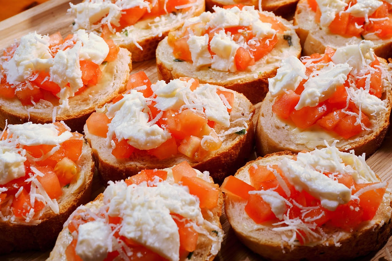 Bruscatelle dorate e croccanti impilate su un piatto bianco, con gocce di olio extravergine brillante sulla superficie e grani di sale marino grosso visibile
