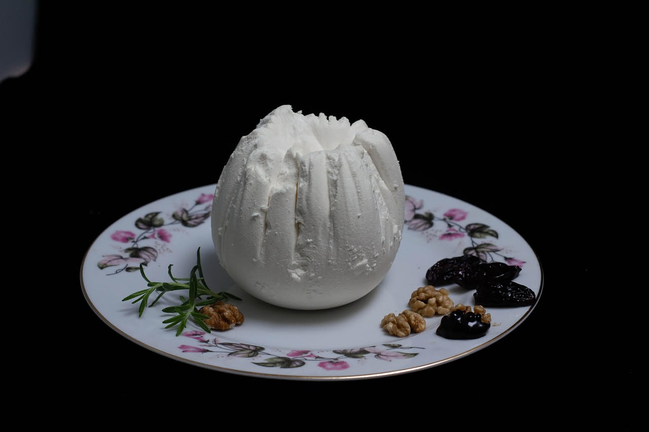 Burrata toscana fresca tagliata a metà su piatto bianco, con il cuore di cagliata e crema visibile, circondata da pomodori rossi e basilico verde