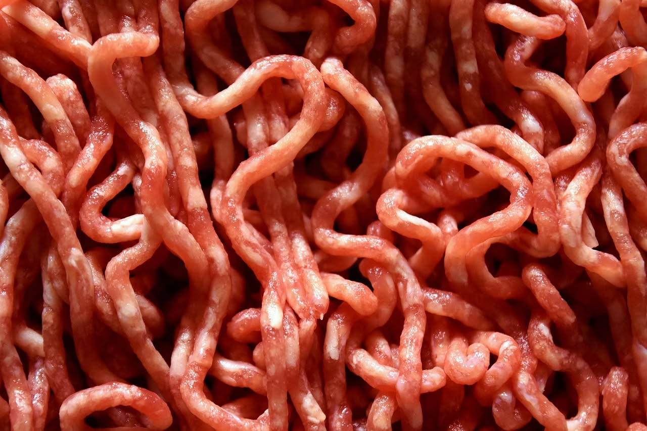 Piatto di busiate al ragù di carne: pasta riccioluta dorata avvolta intorno a sé stessa, ricoperta di ragù marrone scuro con pezzetti visibili di carne, grattugia di formaggio bianco in cima, servito