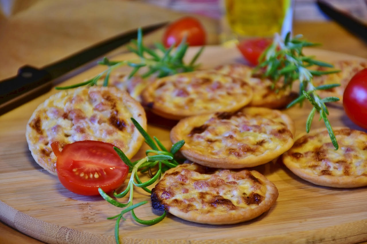 Cacciatorini dorati e croccanti disposti su un piatto bianco, alcuni spezzati in due per mostrare la consistenza friabile, con uno sfondo di tavolo in legno naturale