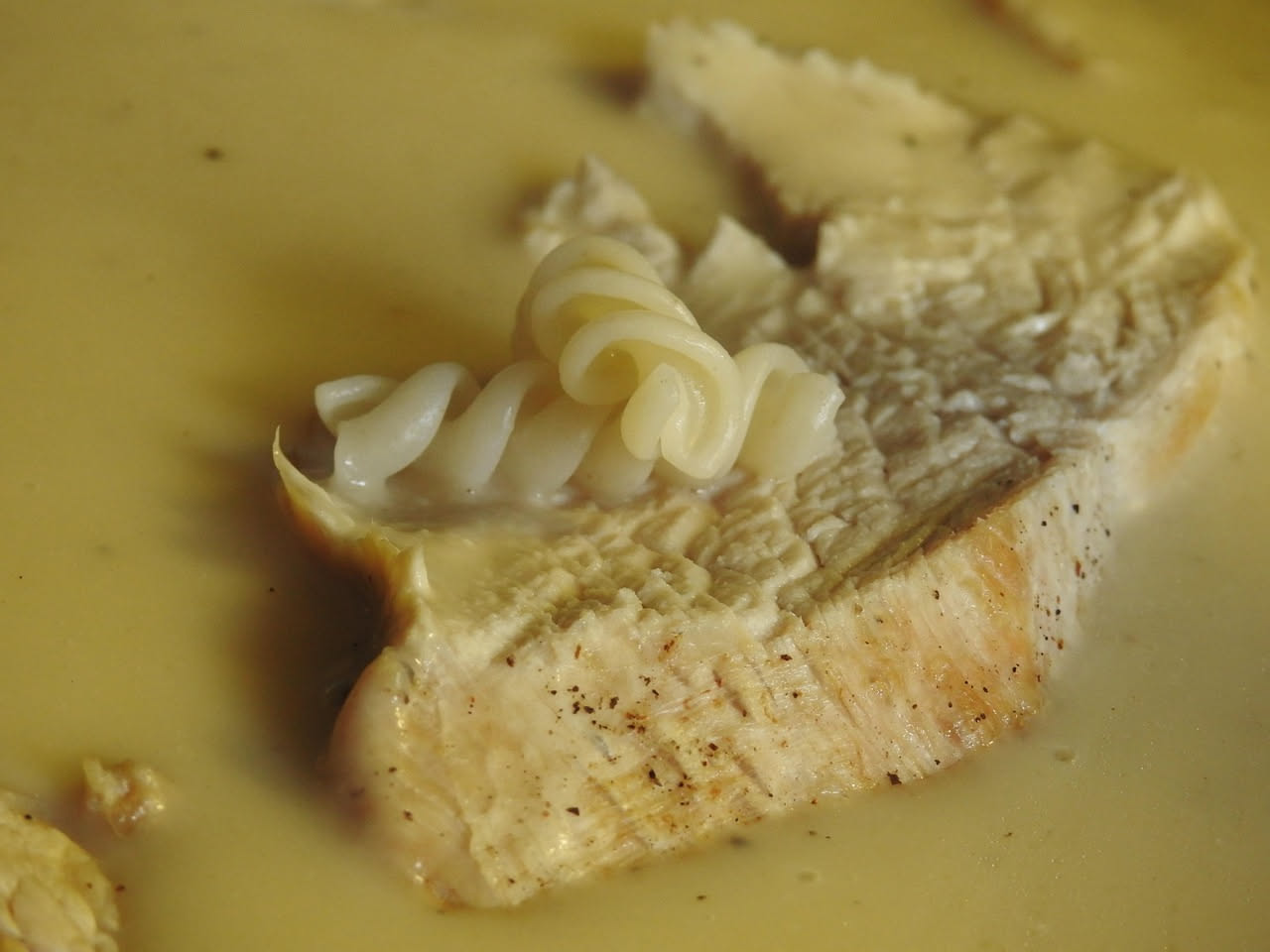 Caciocavallo intero bollito bianco e cremoso nel piatto, con brodo caldo attorno, contornato da salsa di pomodoro leggera e prezzemolo fresco tritato