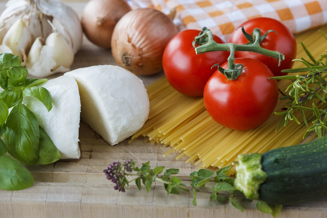 Caciocavallo di Podolica a forma di pera appeso con spago, crosta nocciola, sezione interna crema con pasta filata visibile, tagliato a fette su piatto bianco con olio di oliva