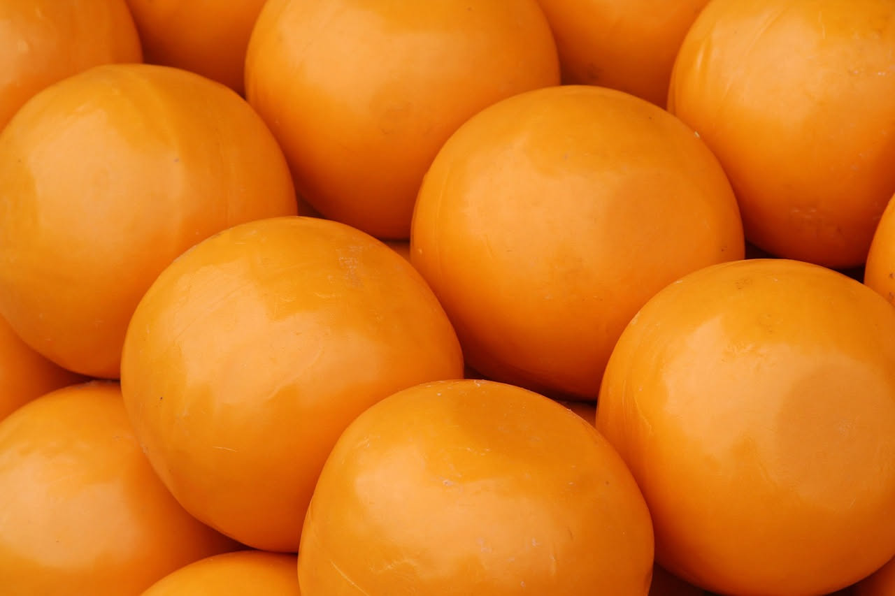 Caciocavallo silano intero di forma tonda e pera su tavolo di legno, colore giallo dorato, con segnature da legatura ben visibili e superficie liscia e lucida