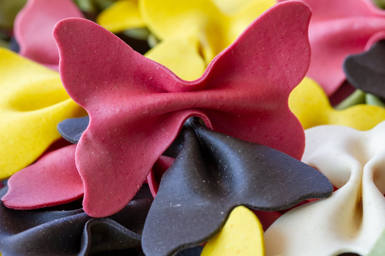 Caramelle modenesi trasparenti e ambrate con pezzetti visibili di frutta candita, sparse su una superficie di marmo bianco, alcune ancora tiepide con lievissima brillantezza di zucchero