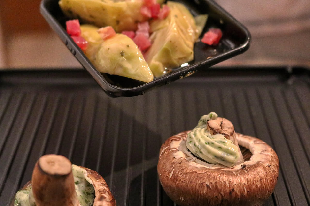 Carciofi alla vicentina nel piatto: spicchi di carciofo dorato con aglio e prezzemolo verde, cotti in umido, in un fondo di brodo ristretto, serviti in una ciotola di ceramica bianca