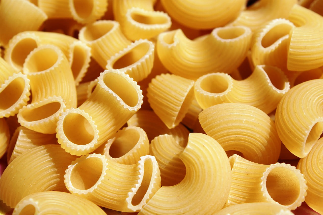 Piatto di cavatappi al ragù messinese: pasta rigatata di colore dorato ricoperta da ragù marrone scuro con frammenti di melanzane viola e viola-nere, cosparsa di formaggio bianco grattugiato, impiatta