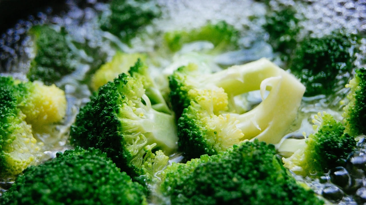 Piatto di cavatelli ai broccoli con pezzi di broccolo verde, aglio dorato e olio d'oliva, serviti in una ciotola di ceramica bianca su tavolo di legno