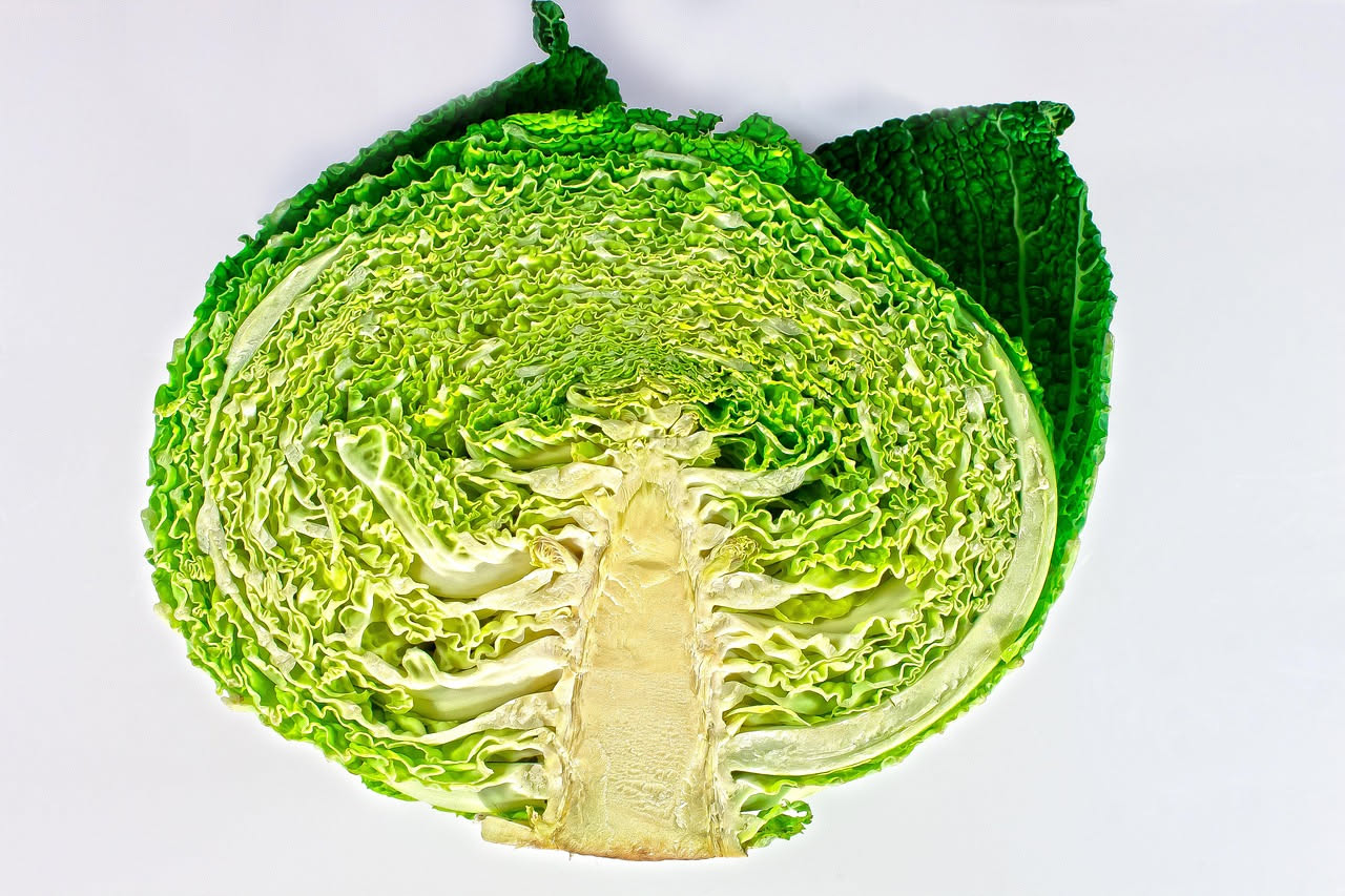 Cavolo verde tagliato a strisce larghe, rossolato in padella con aglio dorato e olio, vapore leggero che sale dal pentolame