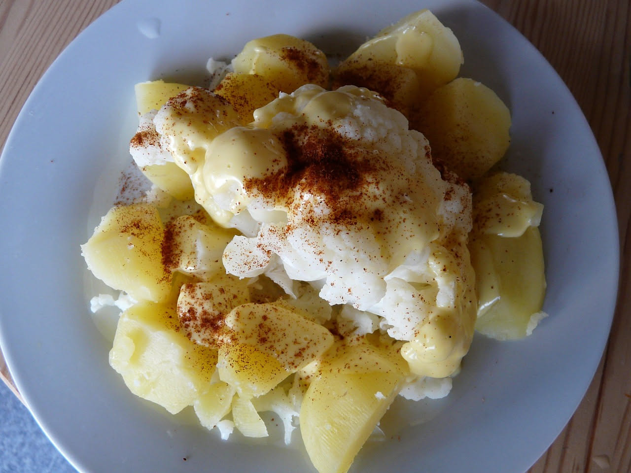 Ciotola bianca con rosette di cavolfiore bianco tagliato finemente, cipolla rossa sottile, olio dorato e aceto, guarnito con prezzemolo fresco verde