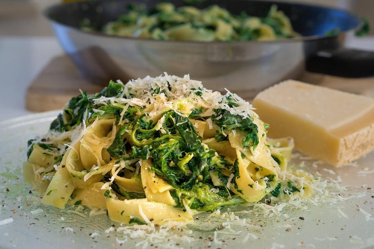 Cicoria lessa scura e uniforme, ancora fumante, condita con olio extravergine d'oliva e sale, su un piatto bianco