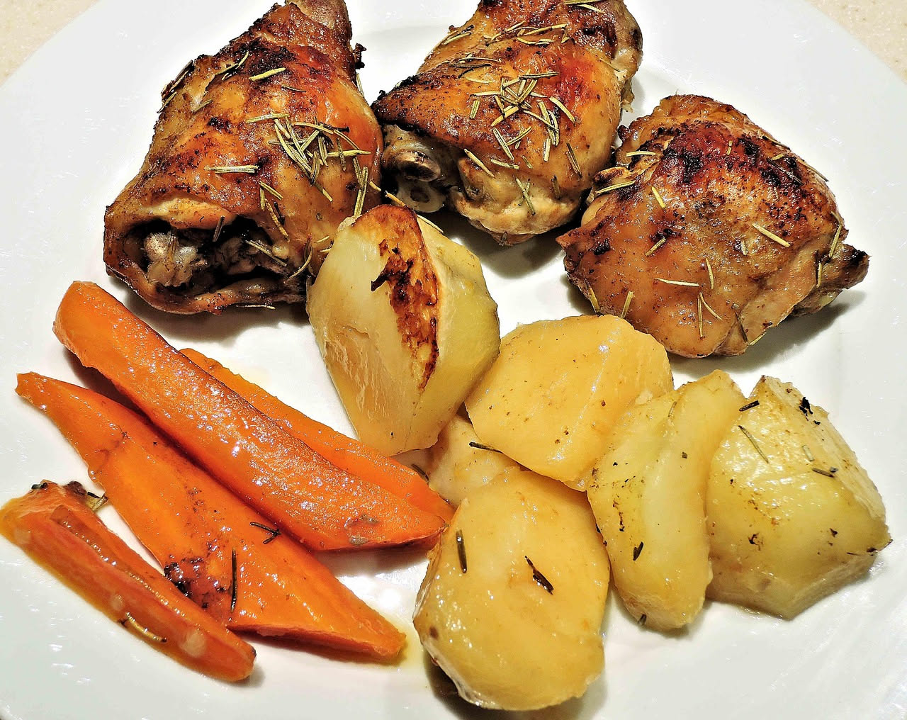 Coniglio in porchetta intero, dorato e croccante in superficie, avvolto in pancetta brunita, su piatto bianco con contorno di verdure grigliate