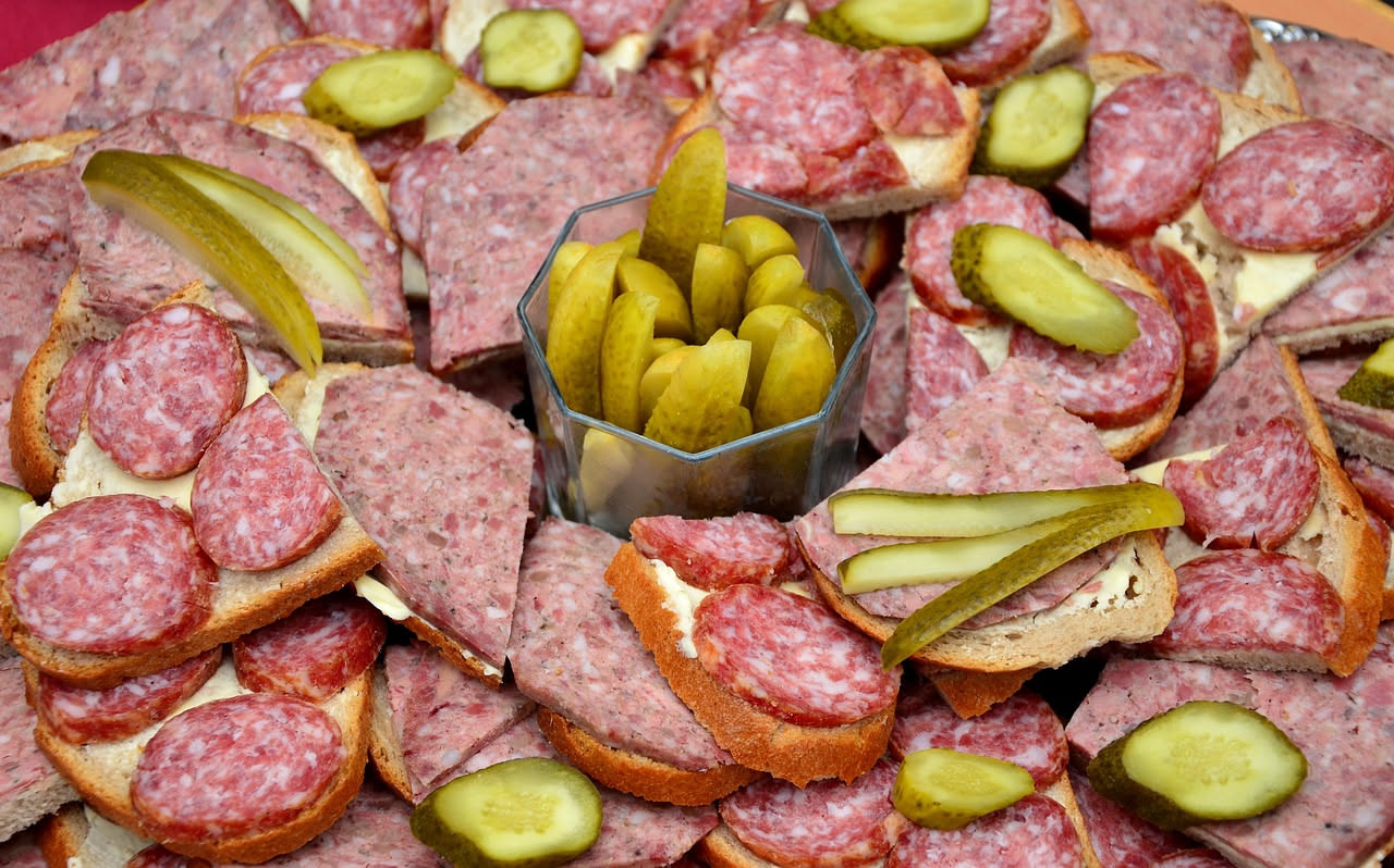Cotechino di Bassano affettato nel piatto, di colore rosato con venature di grasso bianco, accompagnato da purea di fagioli bianchi, contorno di spinaci saltati e brodo caldo in tazza di porcellana