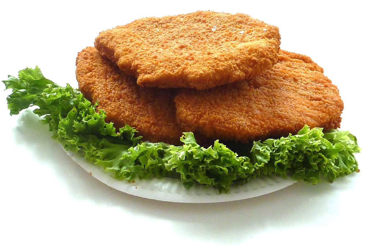Tre cotolette dorate e croccanti in panatura, disposte nel piatto bianco con limone tagliato e prezzemolo fresco, olio luccicante sulla superficie