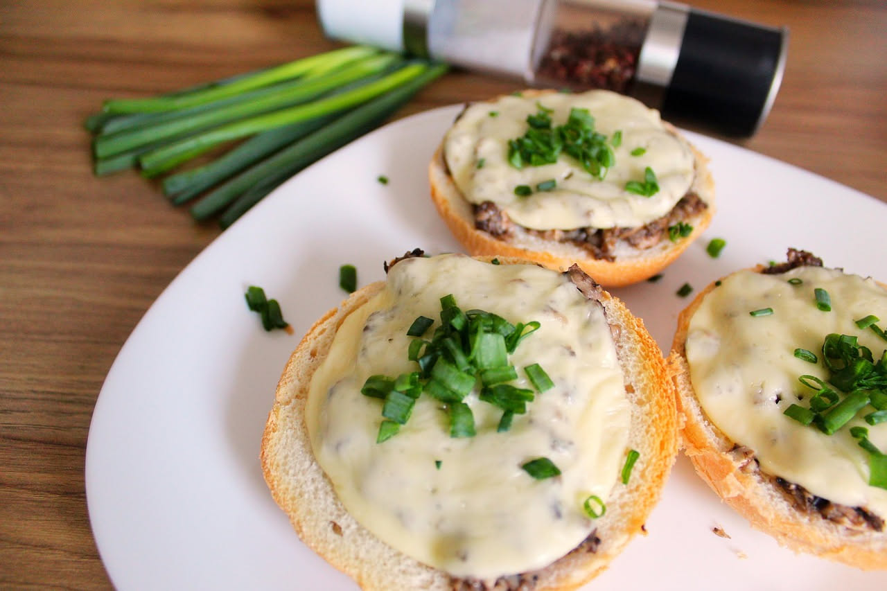 Crostini dorati croccanti conditi con funghi trifolati, aglio fresco e prezzemolo verde su un piatto bianco