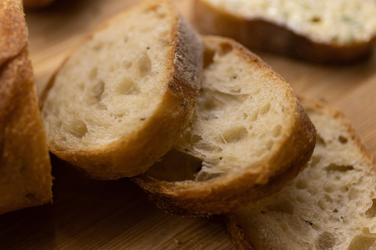 Crostini dorati e croccanti disposti su un piatto bianco, ricoperti di tartufo nero grattugiato e burro, con riflessi lucenti e profilo netto del pane tostato