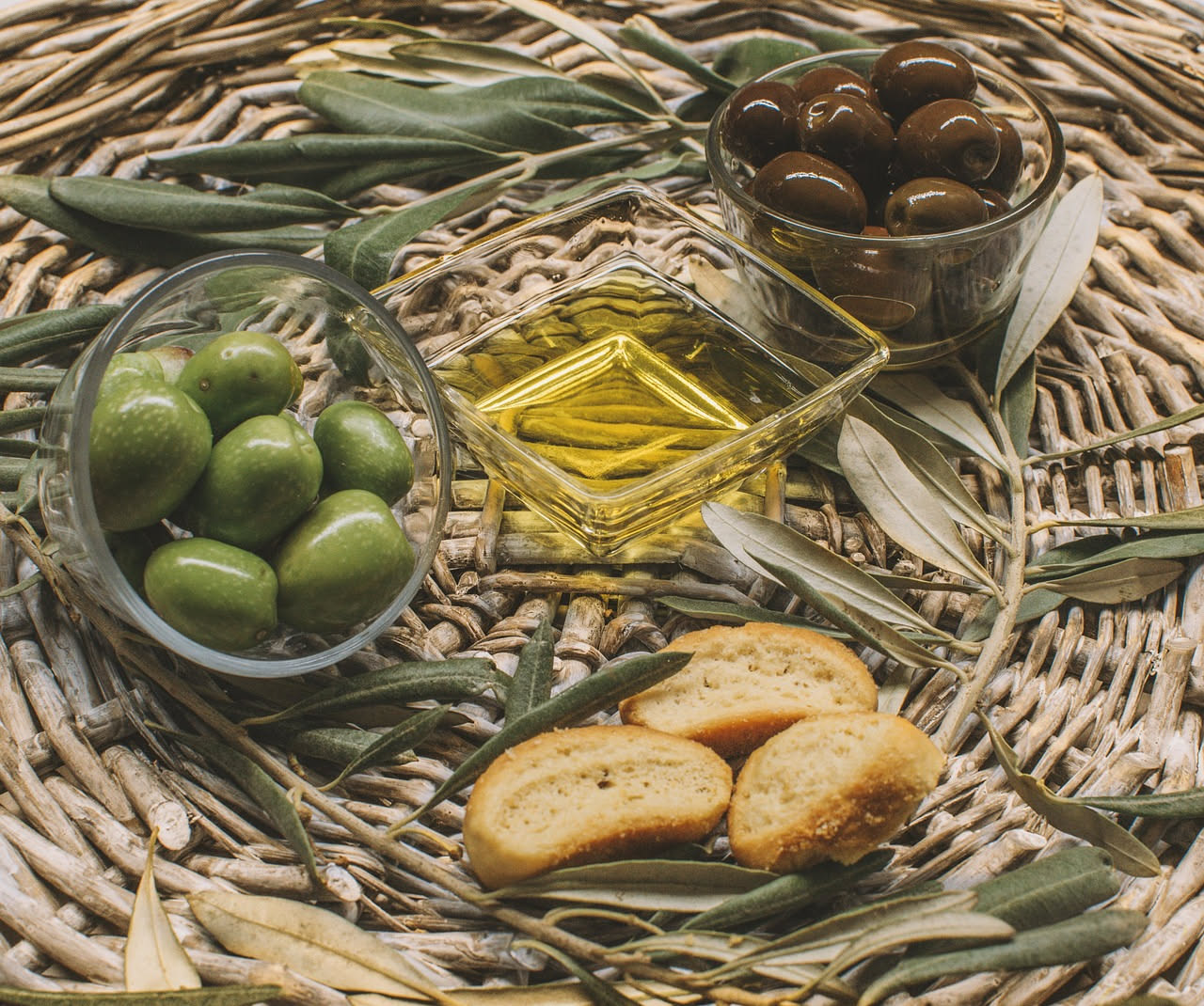 Crostini dorati croccanti ricoperti di crema di olive nera lucida, completati da gocce di olio extravergine, su un piatto bianco con foglie di prezzemolo fresco