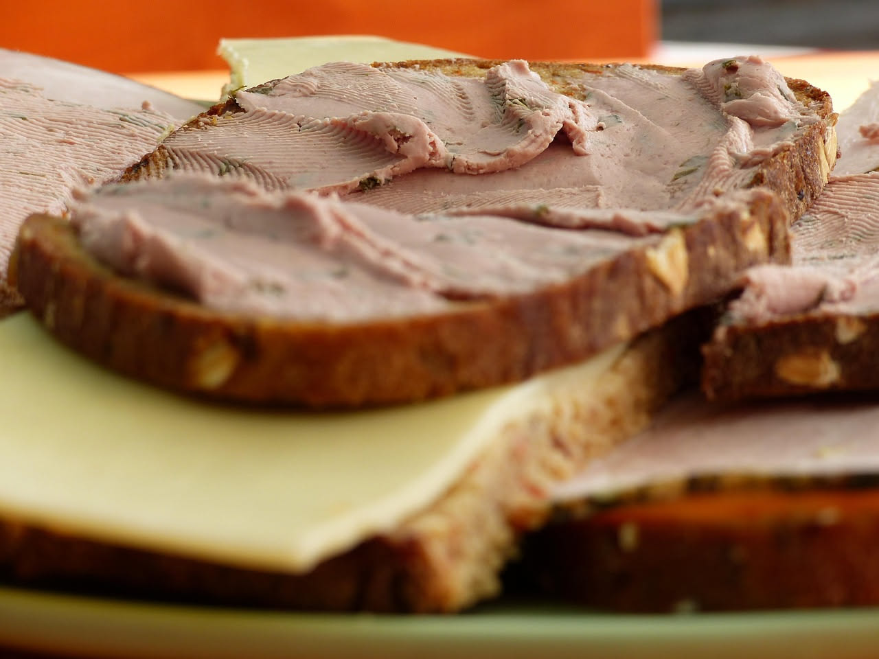 Tre crostini di pane tostato ricoperti di crema di fegato beige chiaro, decorati con un rametto di prezzemolo fresco e gocce di olio dorato su piatto bianco