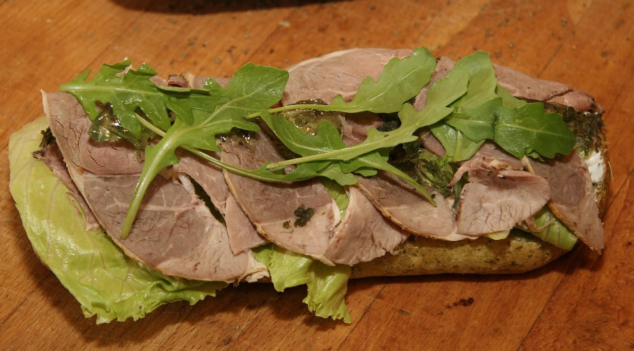 Crostini di pane tostato con crema di milza marrone scuro e speziata, su un piatto bianco con contorno di prezzemolo fresco