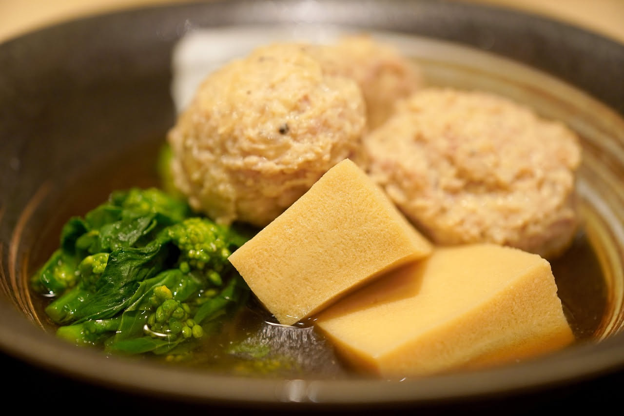 Piatto fondo di ceramica con erbazzone in brodo: riso morbido e verdure verdi immerse in brodo chiaro e fumante, con prezzemolo fresco tritato in superficie e un filo di olio d'oliva