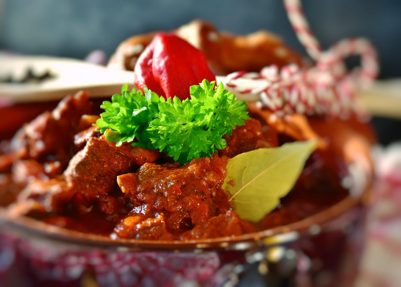 Piatto bianco con fegatini di colore marrone scuro in salsa densa, circondati da verdure cotte e brodo ristretto, con prezzemolo fresco sopra
