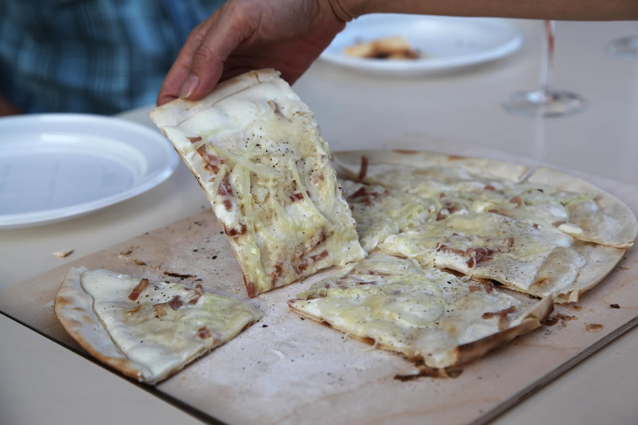 Focaccia di Recco dorata e croccante appena sfornata, tagliata a quadrotti su un piatto bianco, formaggio filante visibile tra gli strati, superficie lucida d'olio
