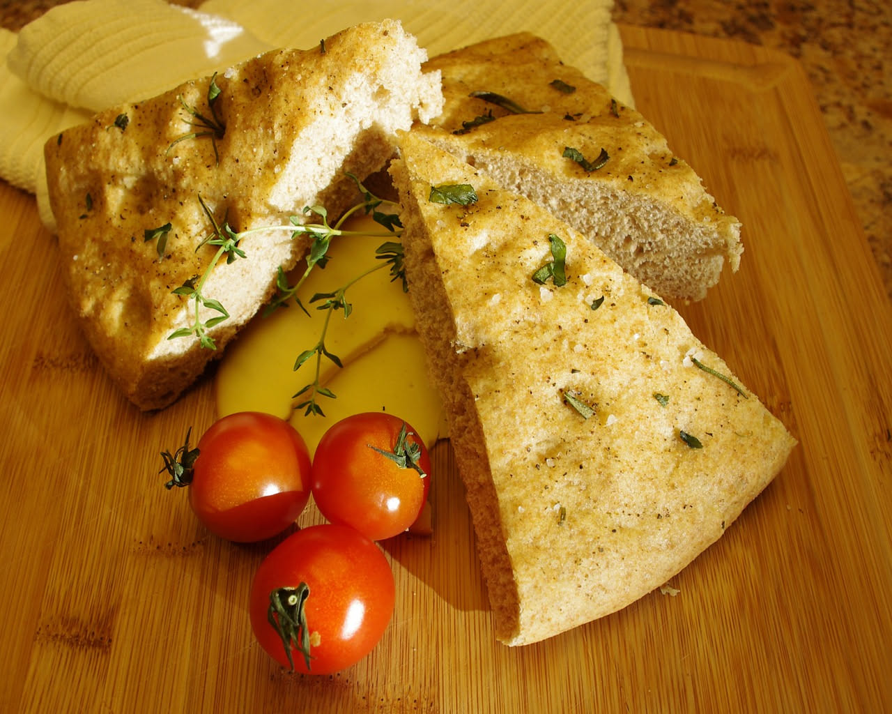 Focaccia toscana dorata con rosmarino fresco e sale grosso sparso in superficie, su piatto di ceramica beige