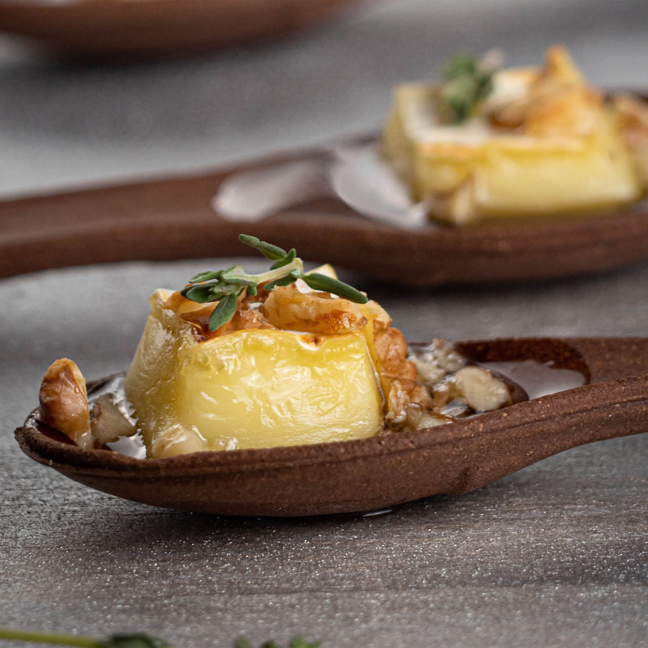 Piatto bianco con cumulo di ricotta cremosa al centro, completato da granuli di pecorino scuro, noci spezzate intorno e un rivolo di miele dorato che scende da sopra. Contorno di pane tostato croccant