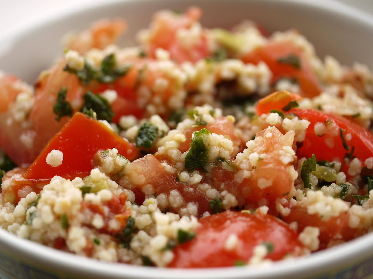 Piatto di fregola con bottarga grattugiata in superficie, grani dorati di semola con crosta salata, condimento di olio extravergine e bottarga grattuggiata dal colore giallo-arancio, servito in piatto