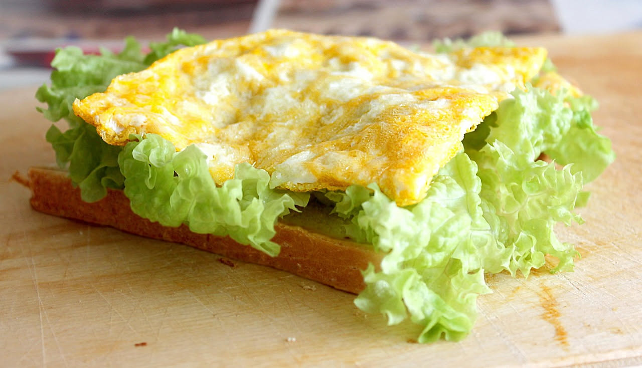 Frittata di scarola dorata in padella antiaderente, con scarola verde che spunta dai bordi, completamente cotta e servita nel piatto bianco