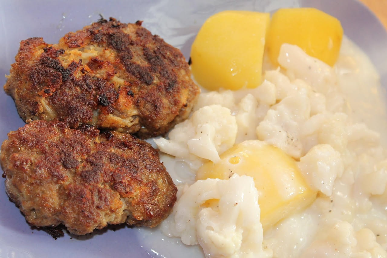 Frittelle di cavolfiore dorate e croccanti in piatto bianco, con interno bianco e superficie dorata, guarnite con sale grosso e fettine di limone fresco
