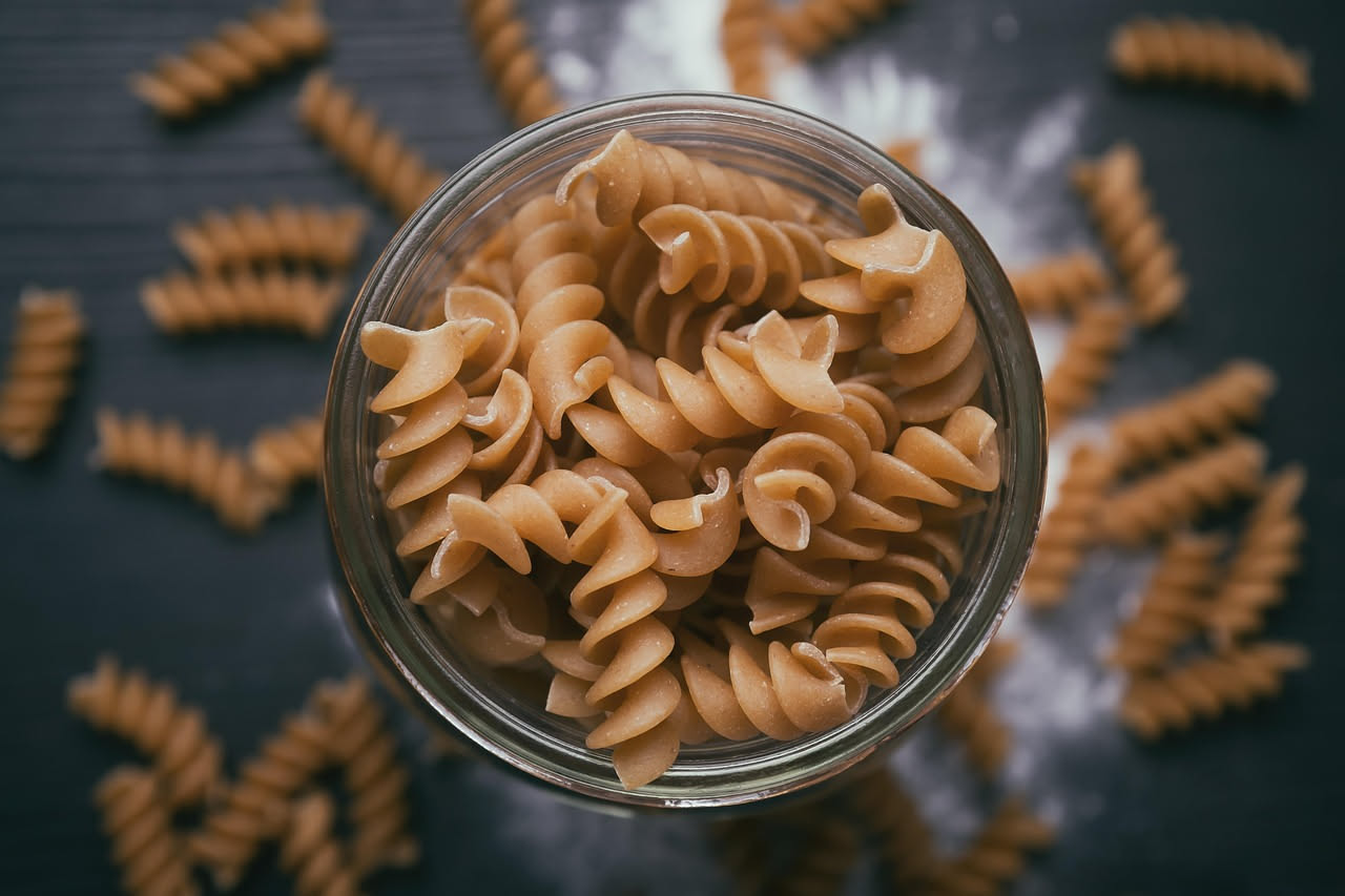 Fusilli cremosi al tartufo nero serviti in piatto bianco, conditi di burro luminoso, pezzetti di tartufo visibili e scaglie di parmigiano grattugiato fresco